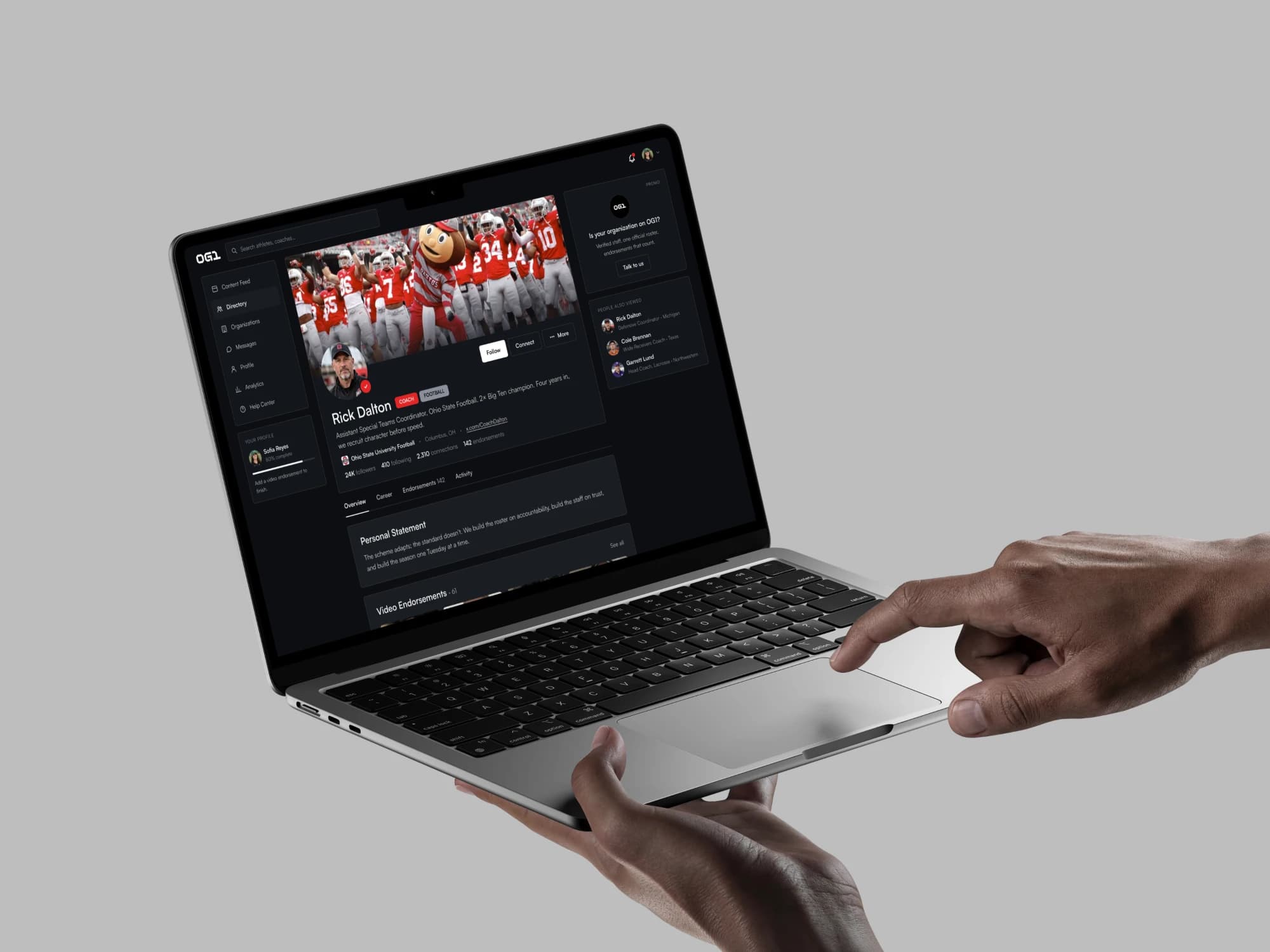 A coach’s OG1 profile on a laptop held in two hands